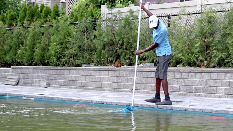 Nettoyage de la surface d'une piscine creusée à l'épuisette